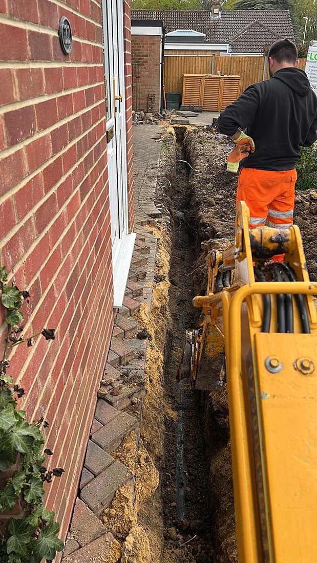 Overflow engineers excavating a collapsed drain beside a Bracknell property